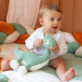 Baby die speelt met zijn muzikale knuffel diplodocus
