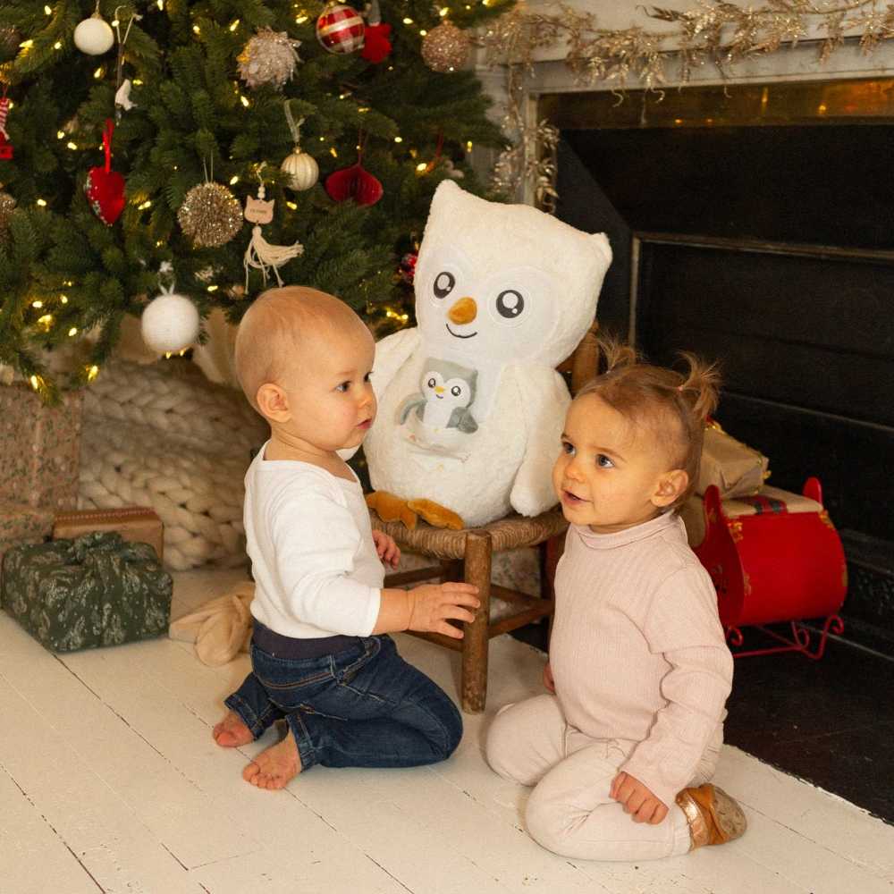 Grote uilenknuffel aan de voet van de kerstboom