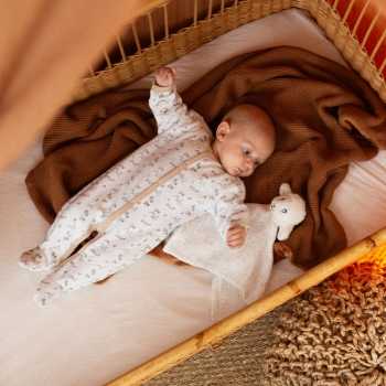 Baby in zijn bedje gekleed in de bergenpyjama met zijn schapenknuffeldoekje