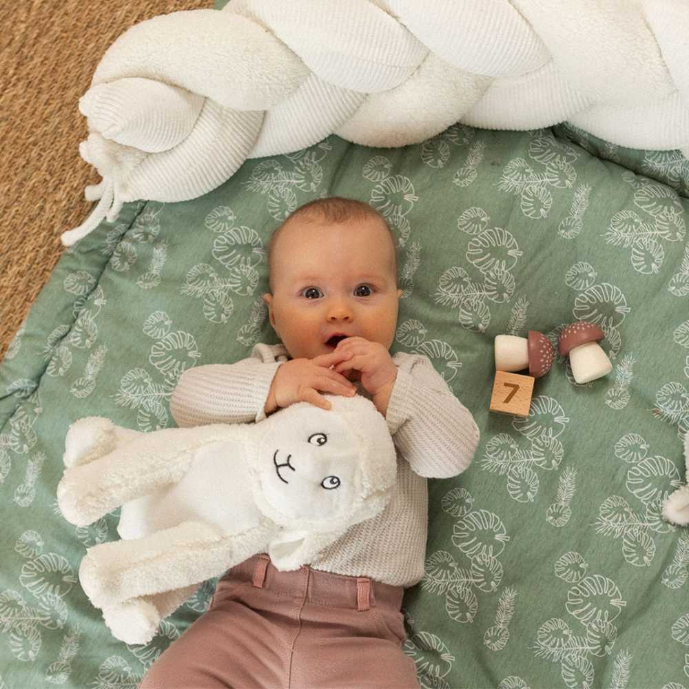Baby mit seinem Schaf-Plüschtier auf seiner Spielmatte