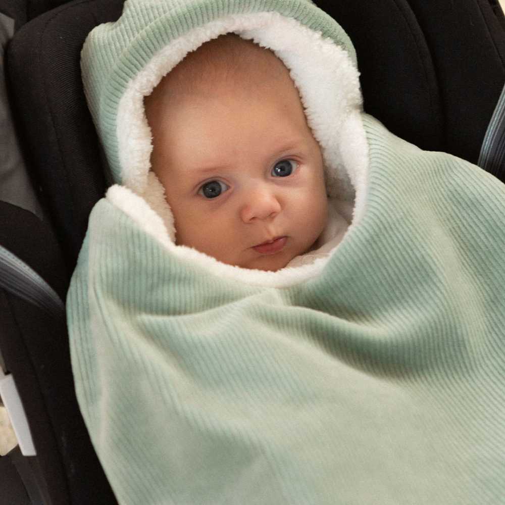 Baby in zijn autostoeltje met zijn voetenzak