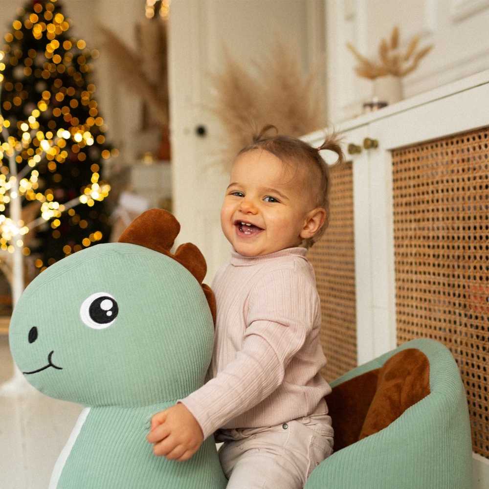 baby op zijn dino schommel bij de kerstboom