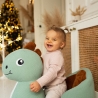 baby on their dinosaur rocking horse at the foot of the Christmas tree