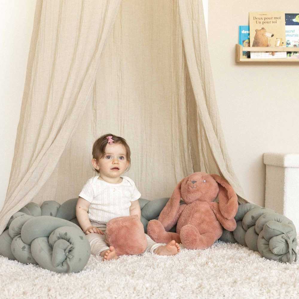 bébé joue avec son cube d'éveil assis entouré de sa tresse décorative