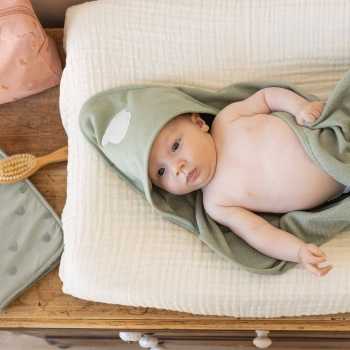 bebé sobre colchoneta cambiador con su capa de baño bebé