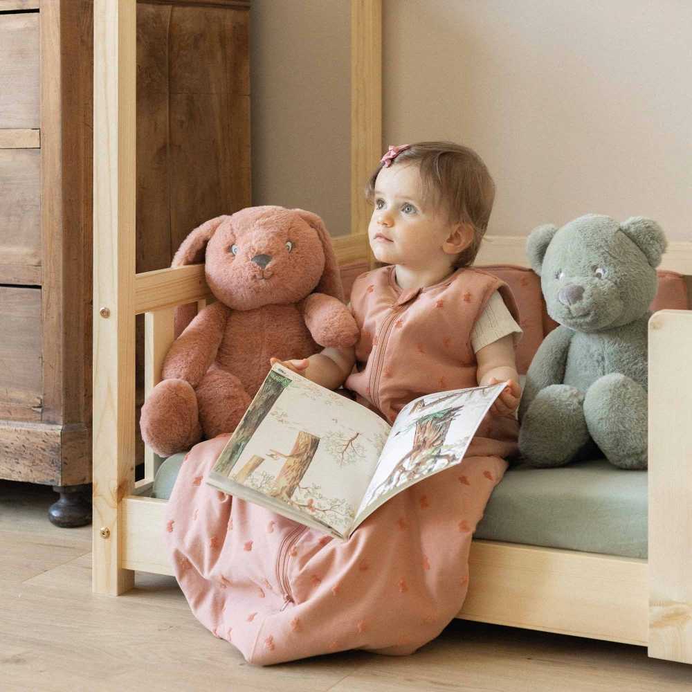 baby zit op de rand van zijn bed met zijn slaapzak