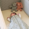 bebé duerme en su saco de dormir verde