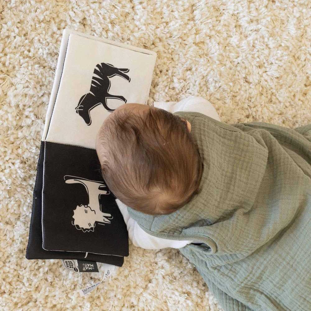 Baby schaut sein Buch in seinem Schlafsack an