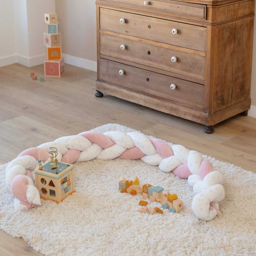 Trenza decorativa blanca y flores rosas delimita el espacio de juego bebé