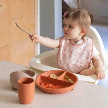 bebé con su babero rosa comiendo