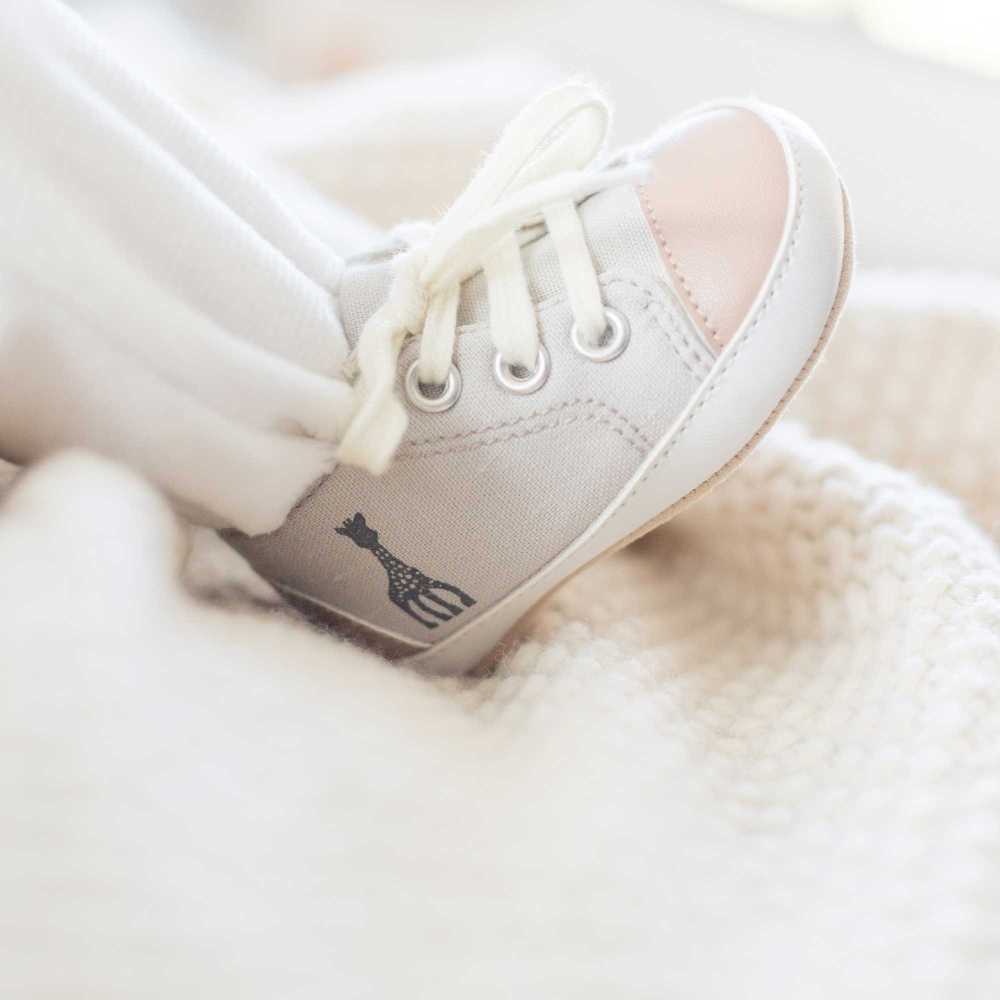 Kleiner Babyfuß mit den Sophie die Giraffe Sneakers