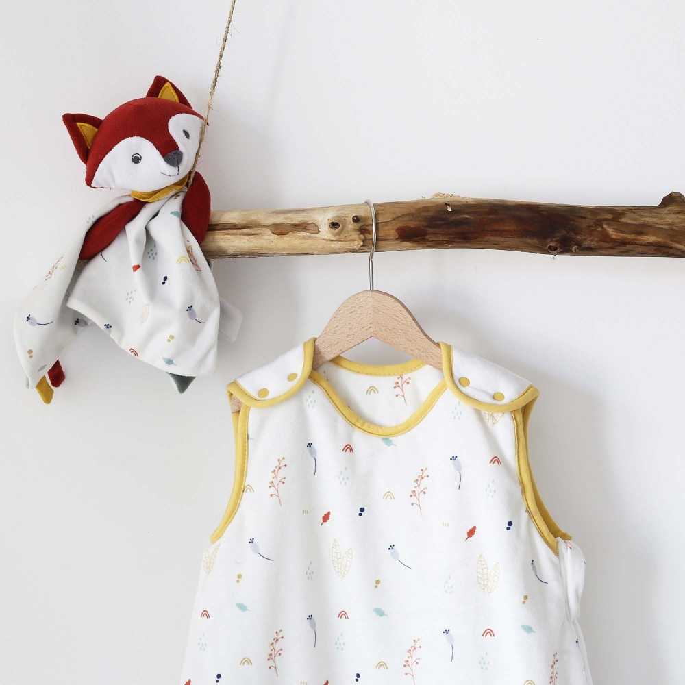 Saco de dormir bebé colgado en un perchero de madera y el doudou Léonard