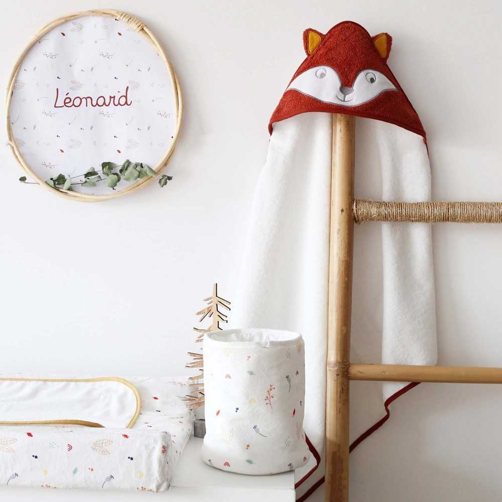 Pequeña bolsa con productos para bebé colocada en la cómoda con la capa de baño zorro