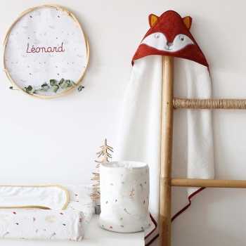 Pequeña bolsa con productos para bebé colocada en la cómoda con la capa de baño zorro