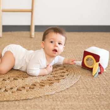 Baby auf Teppich spielt mit seinem Sensorikwürfel.