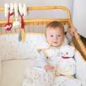 Bébé assis dans son lit en gigoteuse accompagné de sa peluche musicale