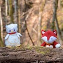 peluche lechuza y el peluche zorro presentados en el bosque detrás de un árbol