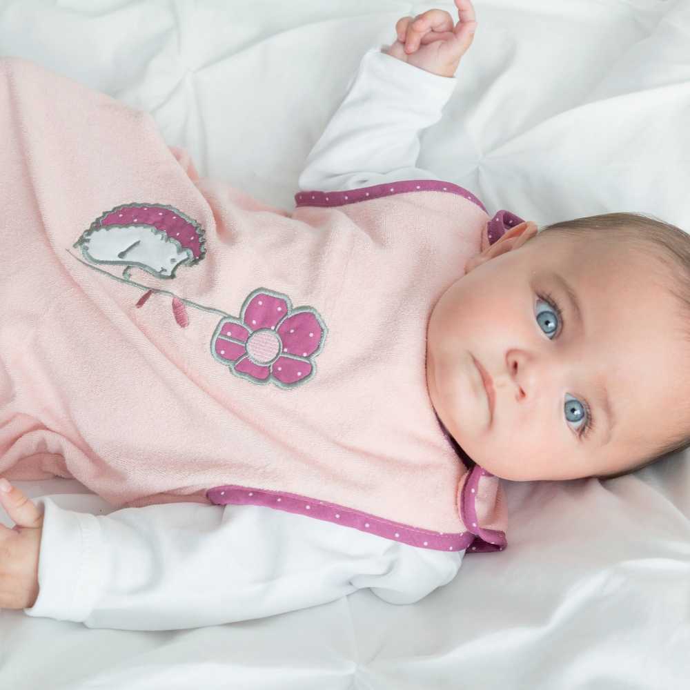 Bambina dagli occhi azzurri e il suo sacco nanna estivo rosa salmone