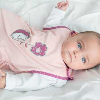 Babymeisje met blauwe ogen en haar zomer slaapzak zalm roze