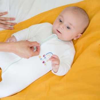 Mama öffnet den Baby-Pyjama mit Reißverschluss