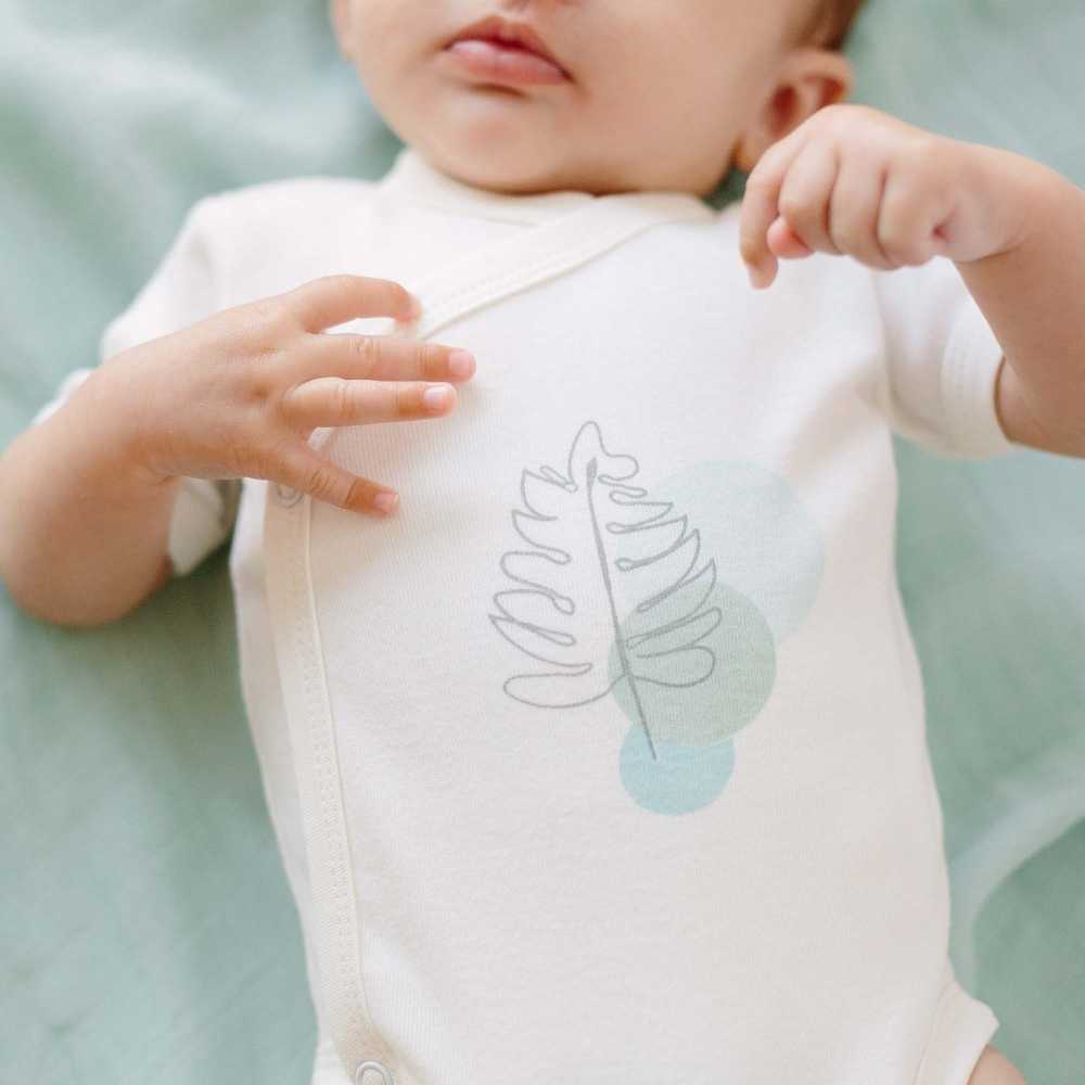 Zoom sur le body écru tropical avec les mains de bébé