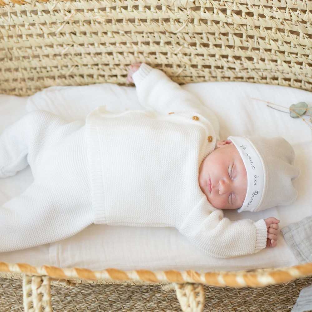 Baby angezogen mit seiner Strickjacke und seiner weißen Strickhose