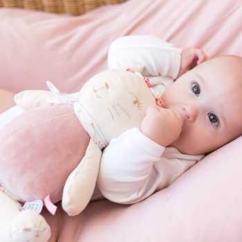 Bébé qui s'endort avec sa peluche musicale Rose dans les bras et son pouce dans la bouche