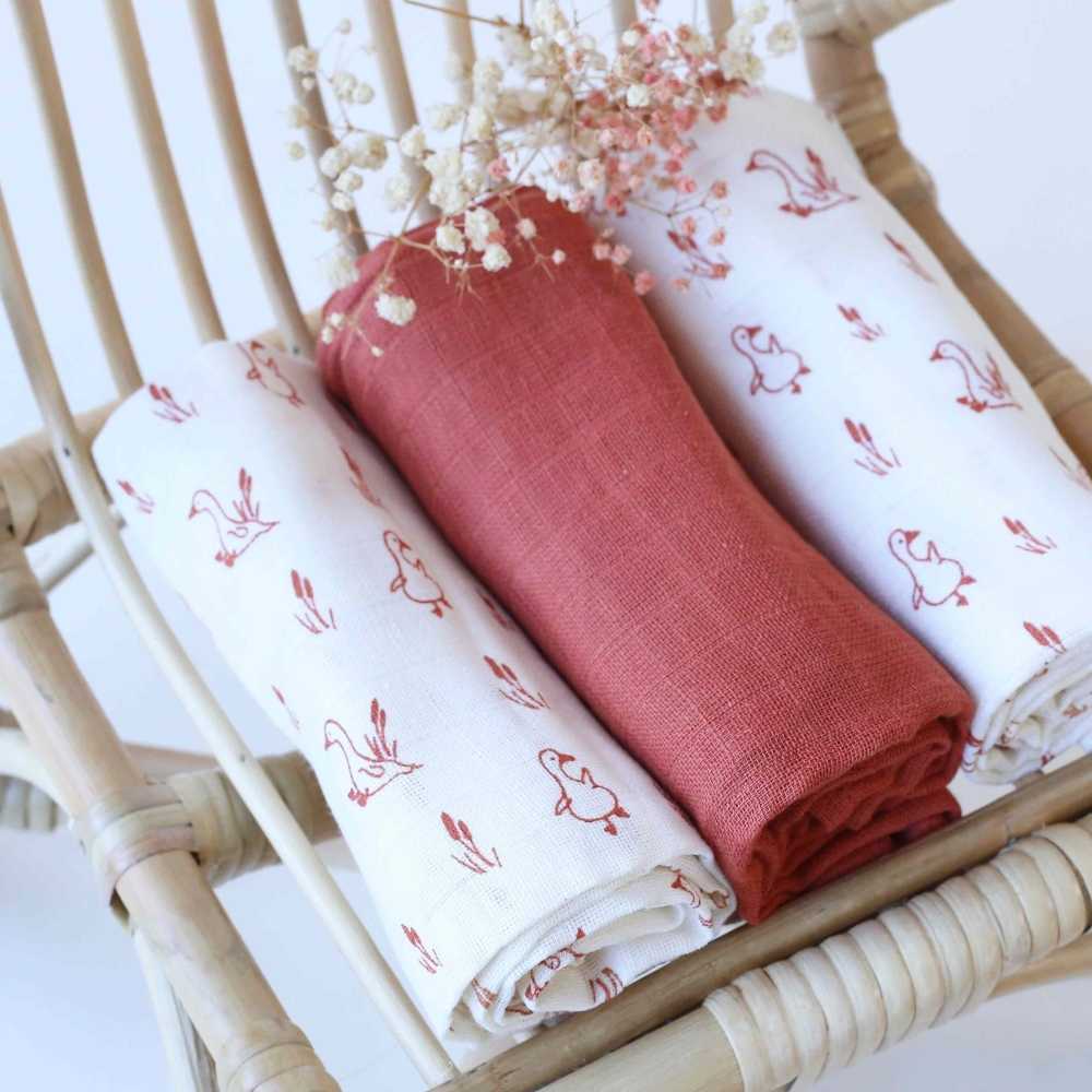 Mise en scène avec le lot de langes sur une petite chaise en rotin pour bébé