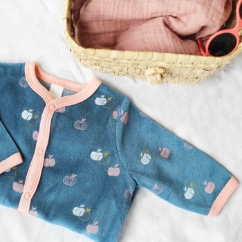 Staged photo of baby girl pajama with a small wicker basket