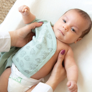 Baby auf seiner Wickelunterlage mit kurzärmeligem Body