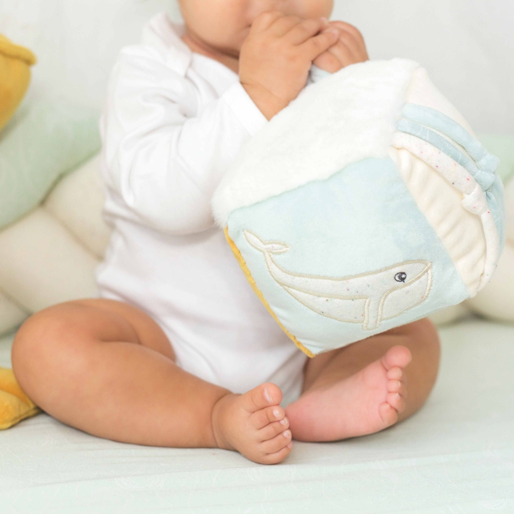 Bébé qui joue avec son cube d'éveil assis sur son tapis