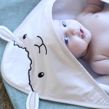 Baby die lacht in zijn baby badcape versierd met klein schaap