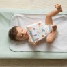 Bébé qui joue avec son livre de bain allongé en couche sur son matelas à langer