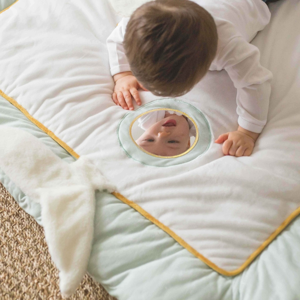 Baby die zichzelf bekijkt in de spiegel van de speelmat